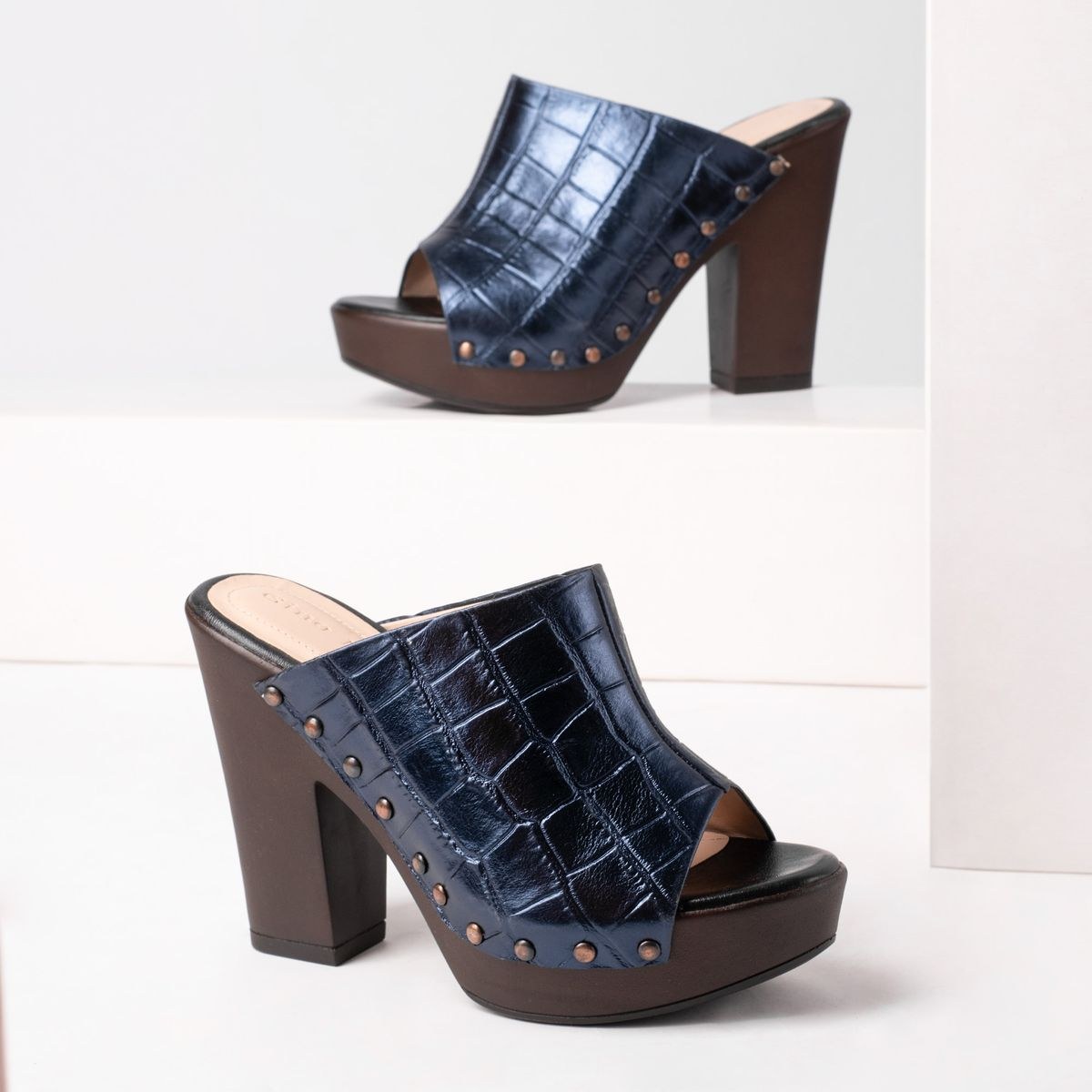 Ejemplo de fotografía de producto: mules azules con tacón sobre pedestal